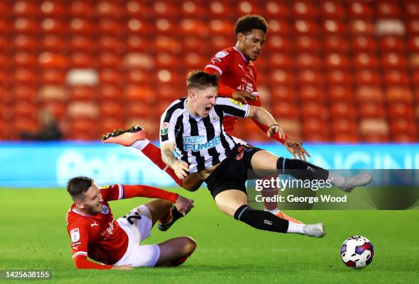 Jay Turner-Cook of Newcastle United U21 is challenged by Conor McCarthy and William Hondermarck of Barnsley during the Papa John's Trophy match...