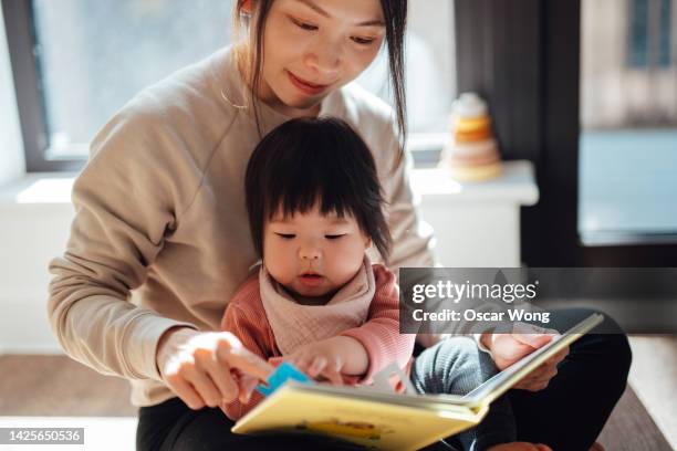 cute asian toddler reading storybook with her mother - 童話 ストックフォトと画像