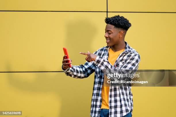 young black man is using his mobile in the street for take selfies - park man made space stock pictures, royalty-free photos & images