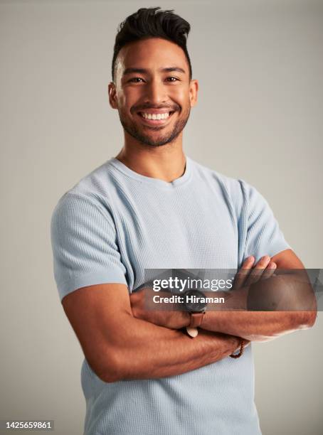 portrait of happy, attractive and positive man with a smile standing with his arms crossed in studio. confident, joyful and young male model with a happiness and positive lifestyle by gray background - charm man stock pictures, royalty-free photos & images