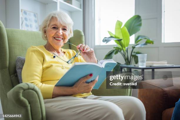 senior frau zu hause - sessel stock-fotos und bilder