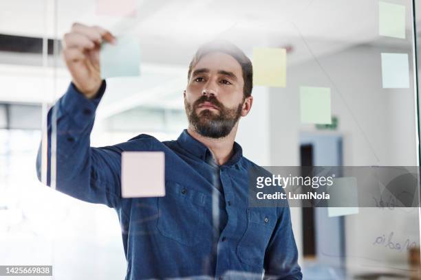 business man planning company growth strategy and development using sticky notes in an office. serious male entrepreneur working on a marketing plan or startup mission or vision at the workplace - mind map stock pictures, royalty-free photos & images