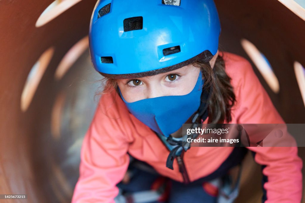 Kid having fun while playing in an obstacle course in an adventure playground.