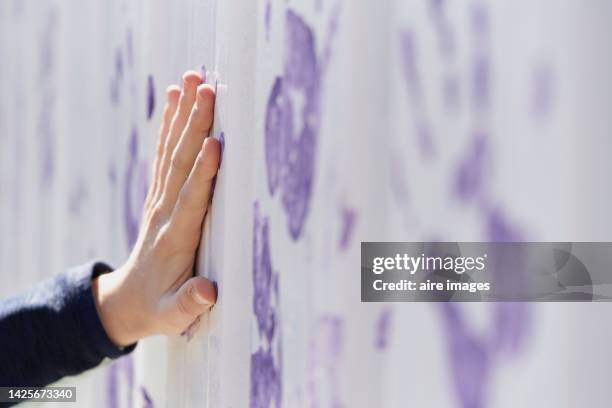 close-up of a person marking handprints on the white wall. - manos pintadas fotografías e imágenes de stock