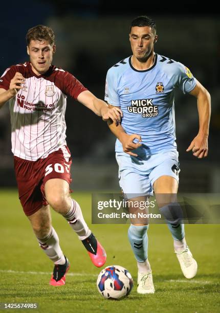 Lloyd Jones of Cambridge United moves forward with the ball away from Jack Connor of Northampton Tow during the Papa John's Trophy match between...