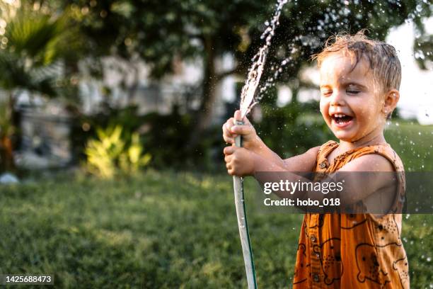 little boy watering garden and having fun spraying water - hose stock pictures, royalty-free photos & images