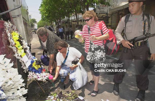 An Indonesia policeman stands guard as foreign tourists lay bouquets of flowers at the blast site in Legian street in the tourist area in Kuta, in...