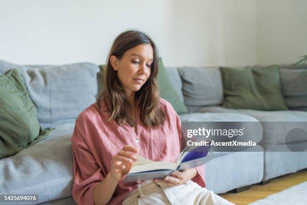 giovane donna legge il libro in salotto - pink blouse foto e immagini stock