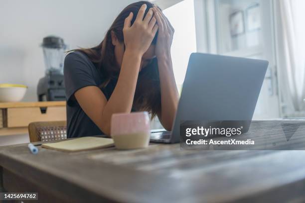 young woman works on laptop at dining room table - head in hands computer stock pictures, royalty-free photos & images
