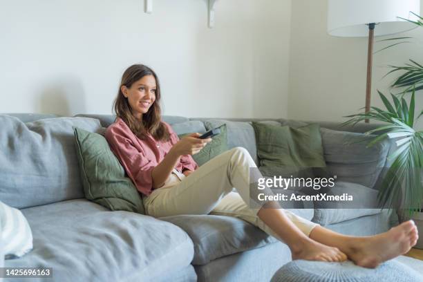 la donna usa il telecomando per la tv in salotto - control pants foto e immagini stock