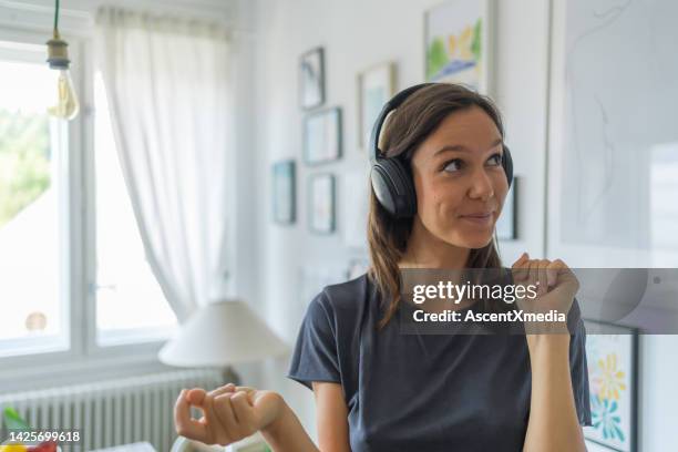 young woman listens to music on headphones, dances - met de vingers knippen stockfoto's en -beelden