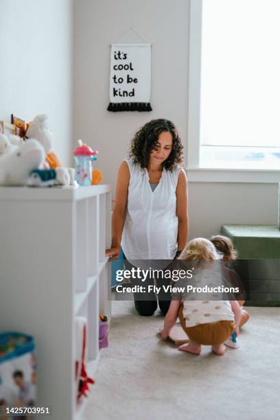 pregnant mom playing with her toddler and her daughter's friend - playroom stock pictures, royalty-free photos & images