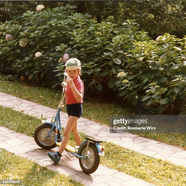 boy standing with his new scooter in garden - ambivere stock pictures, royalty-free photos & images