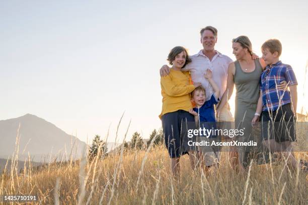 young family in mountain meadow at sunset - family five people stock pictures, royalty-free photos & images