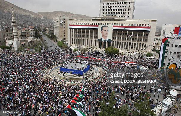 Syrians attend a march to celebrate to anniversary of the founding of the Baath Party and in support of President Bashar al-Assad in Damascus on...