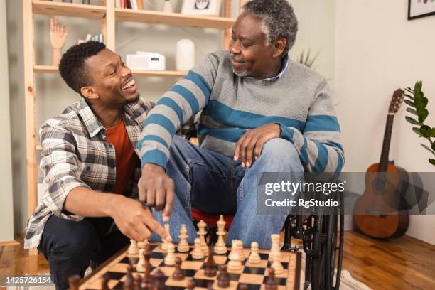 senior african american playing chess with his son - senior playing chess stock pictures, royalty-free photos & images