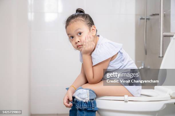 young girl sitting on the toilet - kids peeing - fotografias e filmes do acervo