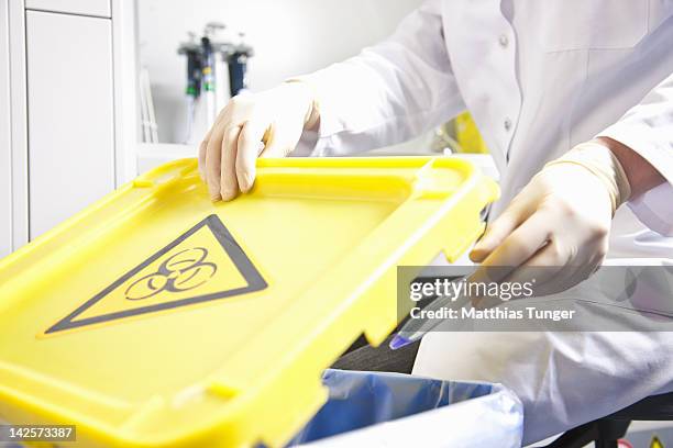 genetic engineer disposing of a contamintated pipe - símbolo-de-riesgo-biológico fotografías e imágenes de stock
