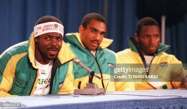 Jamaica's bobsled team member Frederick Powell speaks to newsmen during a press conference as his teammates Michael White and Allen Caswell listen 12...