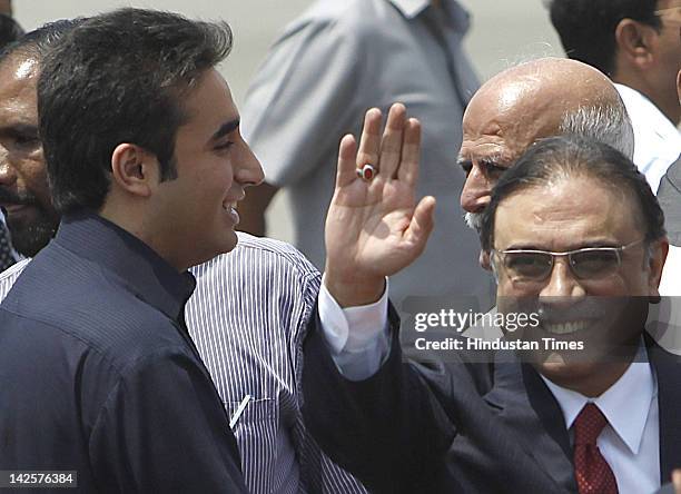 Pakistan's President Asif Ali Zardari waves beside his son and Pakistan People's Party Chief Bilawal Bhutto Zardari as they arrive at Palam Technical...