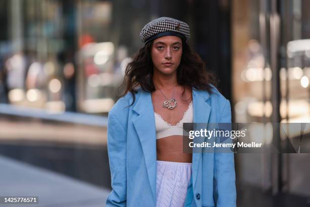 Fashion Week Guest seen wearing a white skirt, beige bralette, white socks with brown heels, a babyblue blazer and an Iphone and a silver shiny bag,...