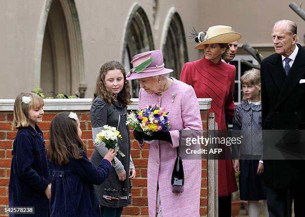 Britain's Queen Elizabeth II receives flowers as she leaves St George's Chapel in Windsor Castle while her husband Prince Philip daughter-in-law,...