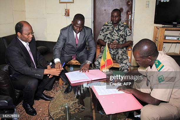 Mali junta leader, Captain Amadou Sanogo signs documents next to Burkina Faso's foreign Minister Djibrill Bassole and Ivory Coast Minister of African...