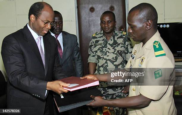 Mali junta leader, Captain Amadou Sanogo exchanges documents with Burkina Faso's foreign Minister Djibrill Bassole next to Ivory Coast Minister of...