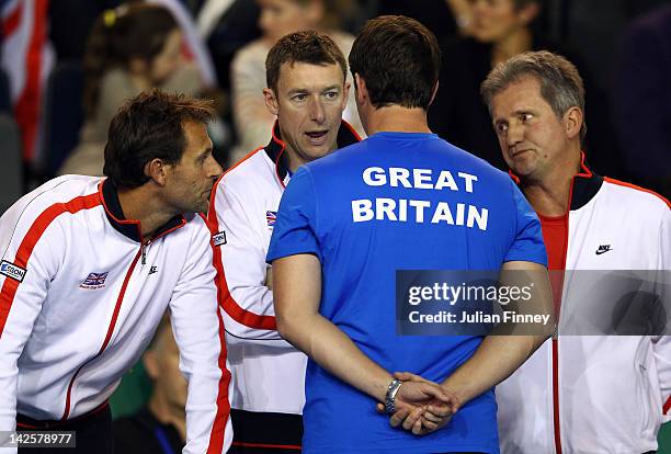 Louis Cayer, Nick Weal and Colin Beecher talk with captain Leon Smith as Josh Goodall of Great Britain takes on David Goffin of Belgium during day...