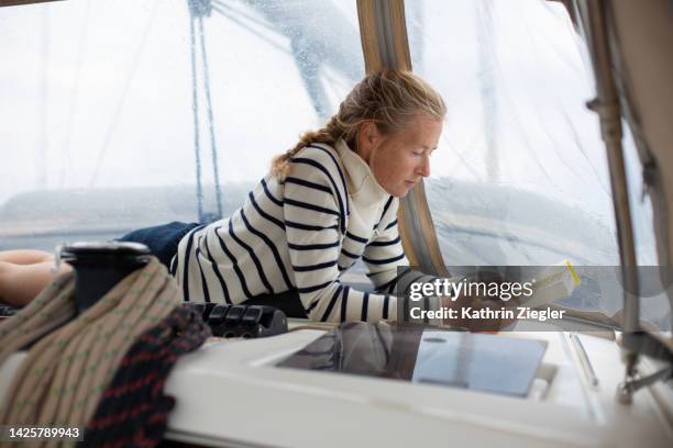woman relaxing on sailboat on a rainy day, reading a book - cashmere stock pictures, royalty-free photos & images