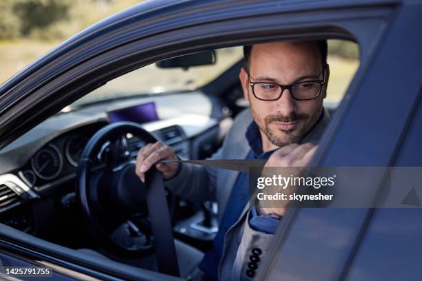 giovane uomo d'affari che allaccia la cintura di sicurezza in un'auto. - laccio foto e immagini stock