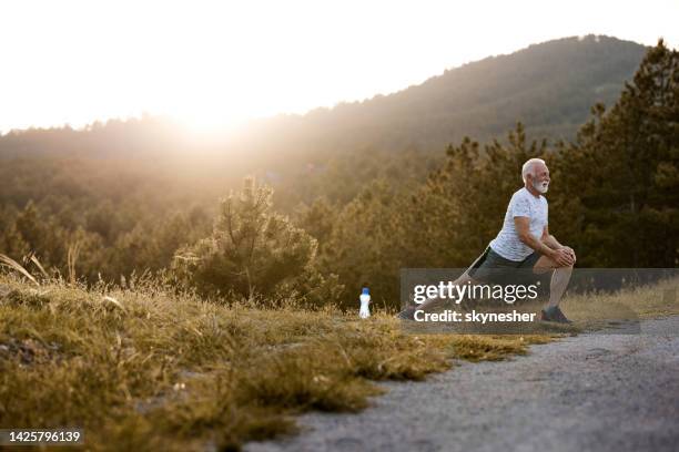 happy senior man stretching after sports training in nature. - groyne stock pictures, royalty-free photos & images