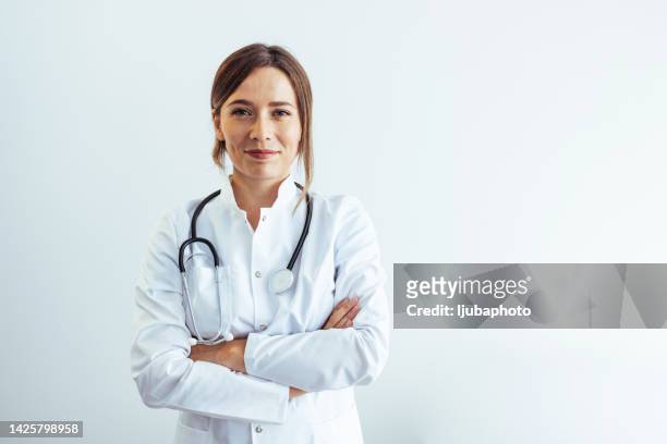 foto einer selbstbewussten ärztin im krankenhaus, die lächelnd in die kamera schaut. - doctor stock-fotos und bilder