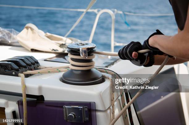 man trimming sail on sailboat, close-up of hands - pull foto e immagini stock