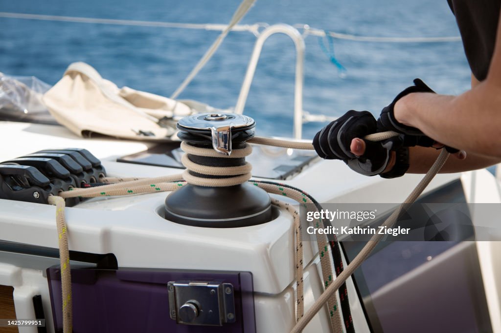Man trimming sail on sailboat, close-up of hands