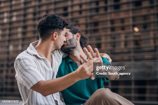 gay couple showing off wedding ring  in the city - wedding ceremony kiss stock pictures, royalty-free photos & images