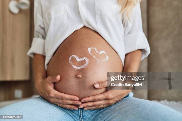 pregnant woman embracing her belly - fetus heart stock pictures, royalty-free photos & images