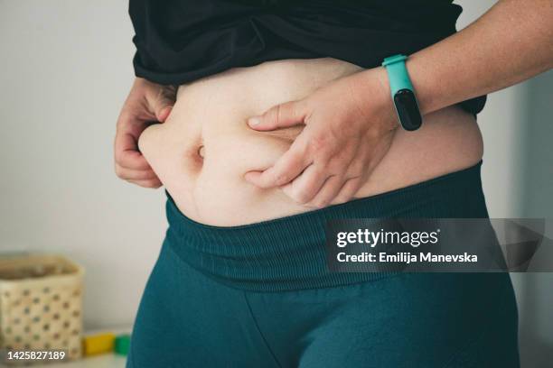 woman hands measuring fat belly - waist stock-fotos und bilder