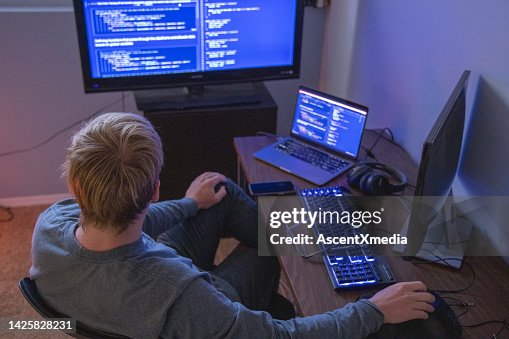 Young man uses multiple computers while coding, developing web site Young man uses multiple computers while coding, developing web site