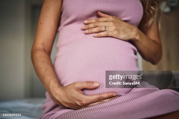 pregnant woman embracing her belly - stroke month stock pictures, royalty-free photos & images