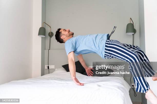 happy man throwing himself into bed to sleep after a long day. - mens long jump - fotografias e filmes do acervo