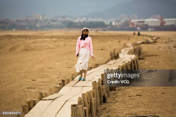 Tourist walks on an ancient bridge which emerges from dried Poyang Lake on September 21, 2022 in Jiujiang, Jiangxi Province of China. The...