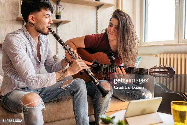 two men playing guitar and clarinet using tablet - duet stock pictures, royalty-free photos & images