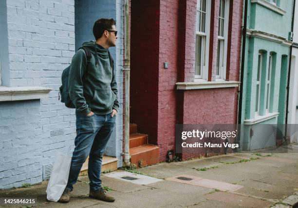 young man shopping in the city, standing in front of building with old facade. - man waiting stock pictures, royalty-free photos & images