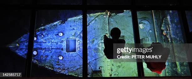 Two children look down on March 27, 2012 at a image of the Titanic wreck in the Titanic Belfast visitor center in the "Titanic Quarter" in Belfast,...