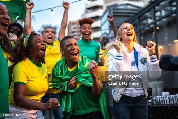 brazilian team fans celebrating on a rooftop bar - a brazil supporter stockfoto's en -beelden