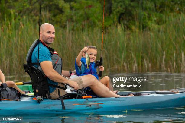 boy holding up smallmouth bass he just caught kayak fishing - zonnebaarzen stockfoto's en -beelden