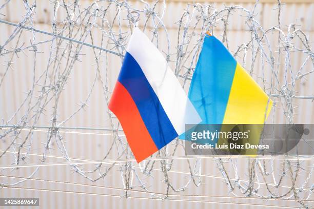 the flag of russia and ukraine hanging on a barbed wire fence - patriotic christmas stock pictures, royalty-free photos & images