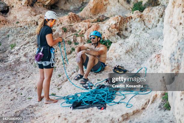 two climbers are at the foot of the mountain. a female climber prepares for a climbing adventure - summit love courage stock pictures, royalty-free photos & images