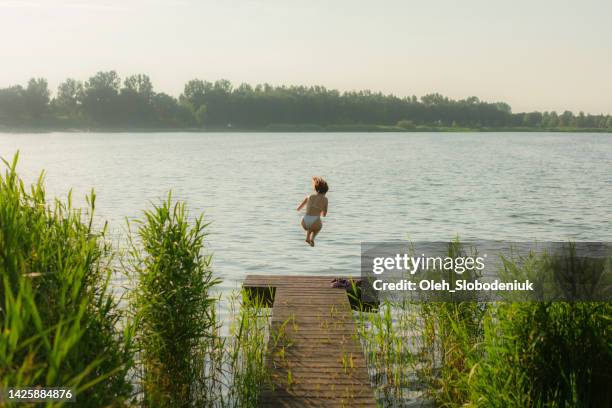 woman running and diving into the lake - running netherlands stock pictures, royalty-free photos & images